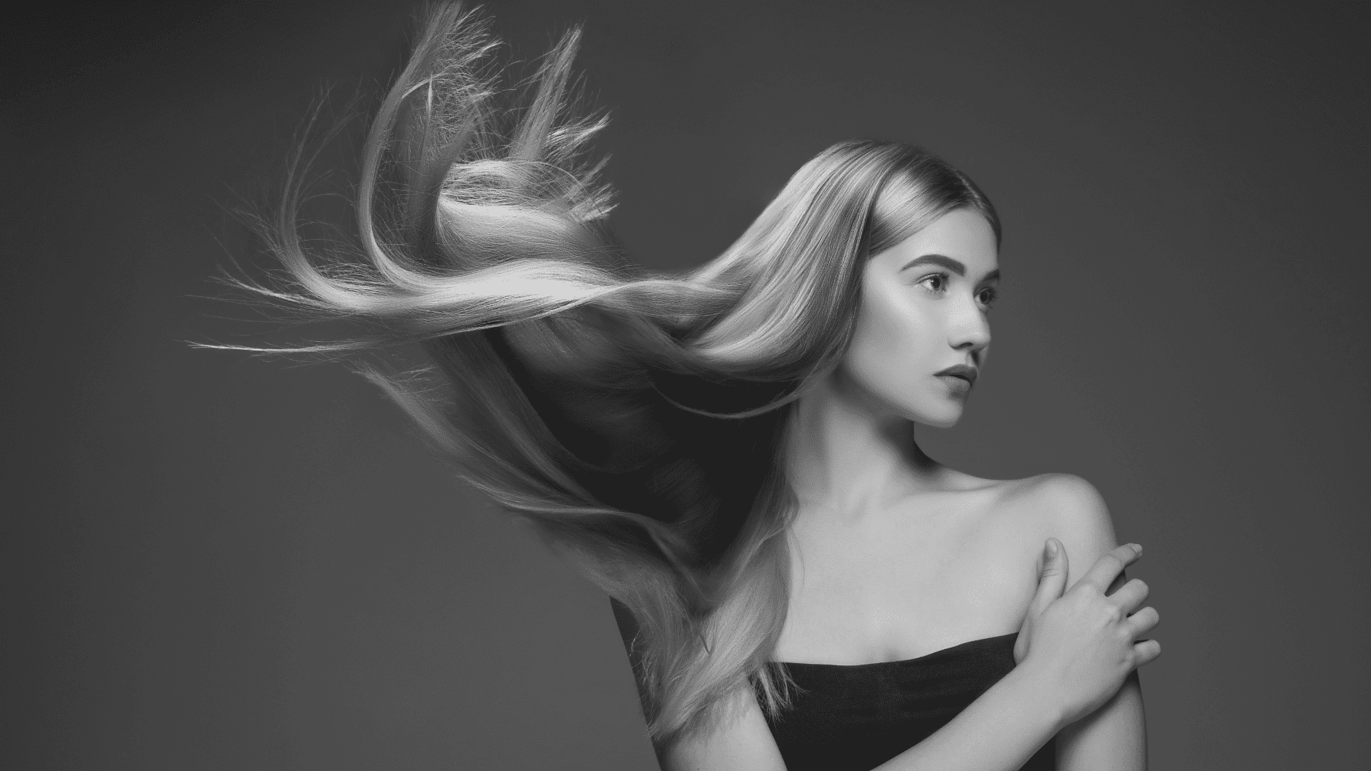 Woman with long, flowing blonde hair against dark background.